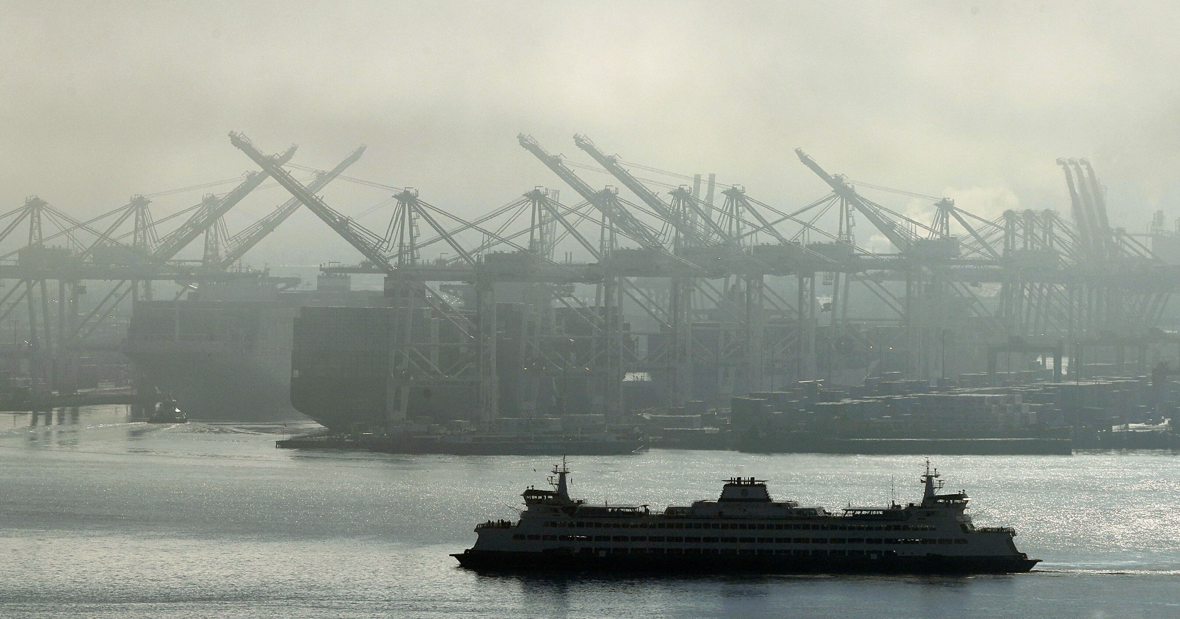 A Washington state ferry sails on Dec. 31, 2018, near cranes at the Port of Seattle.