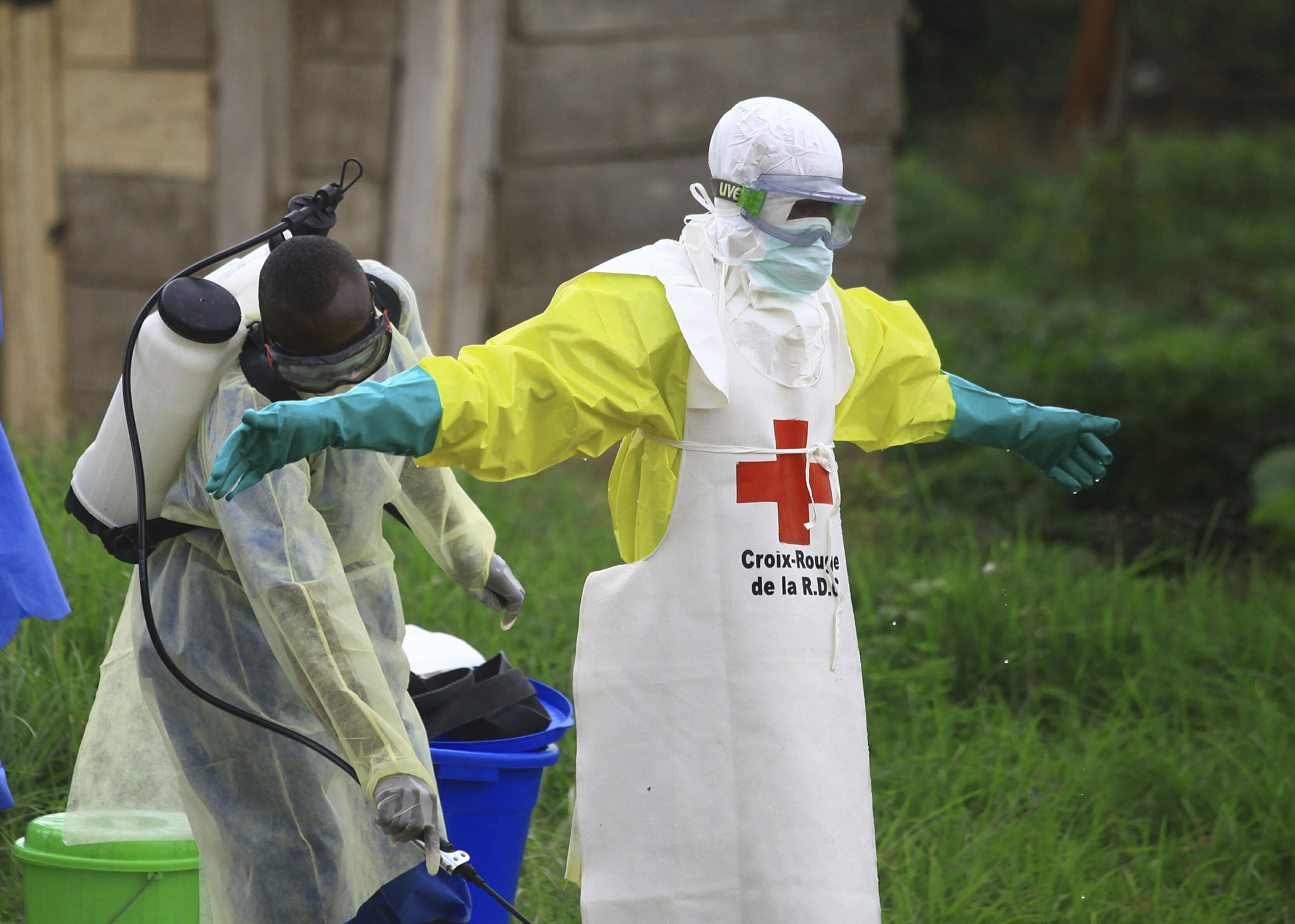 In this Sunday, Sept 9, 2018, file photo, a health worker sprays disinfectant on his colleague after working at an Ebola treatment center in Beni, eastern Congo.