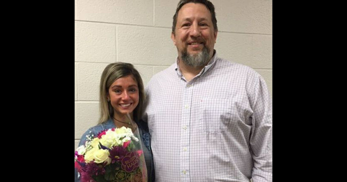 A teary-eyed Lindsey standing next to Putt holding the flowers he gave her.