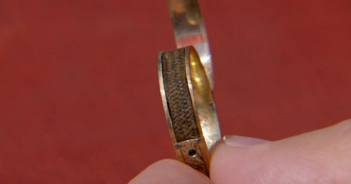The appraiser holds the ring, demonstrating how it can be opened.