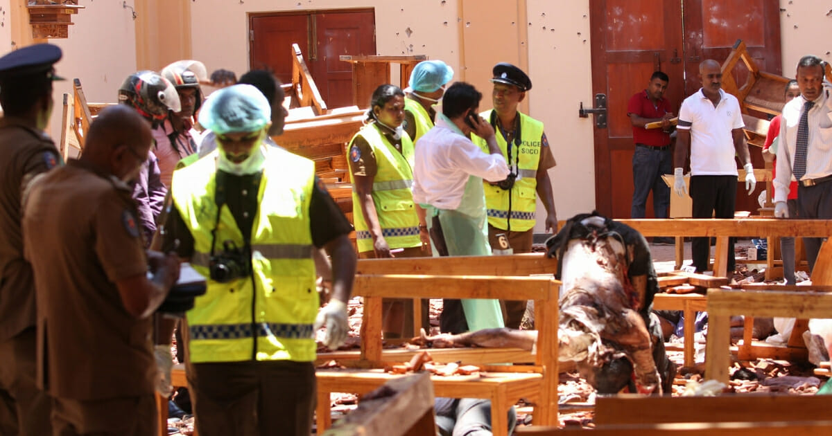 Sri Lankan security personnel walk past debris and bodies following an explosion in St. Sebastian's Church in Negombo, Sri Lanka, on April 21, 2019.