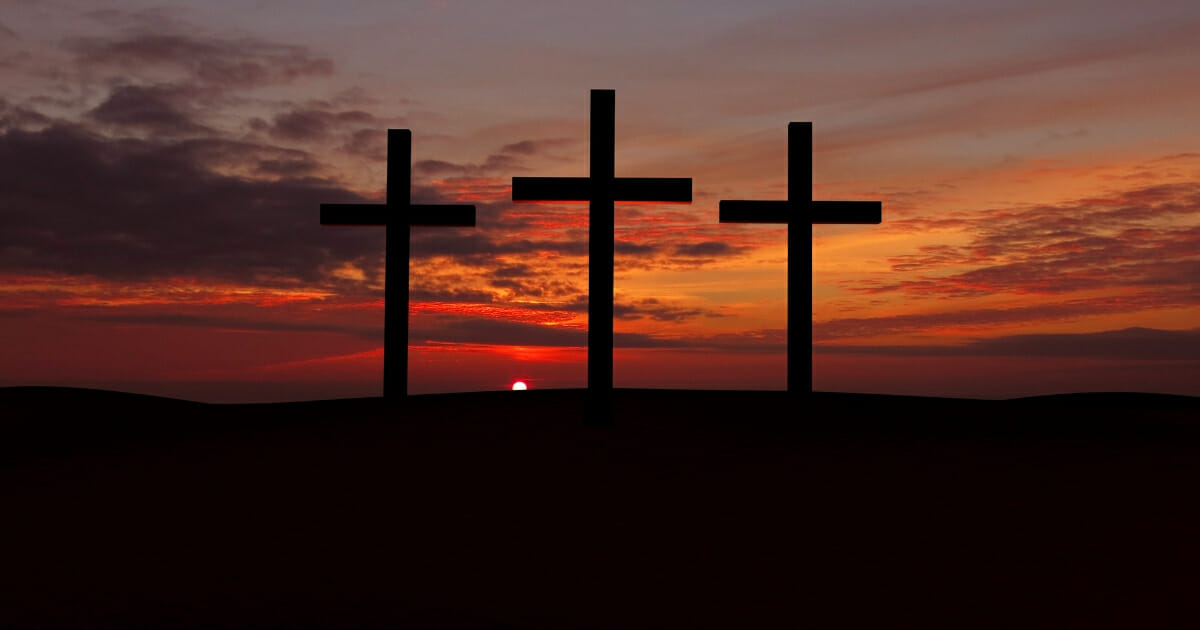 Three crosses on a hill with red sunset.