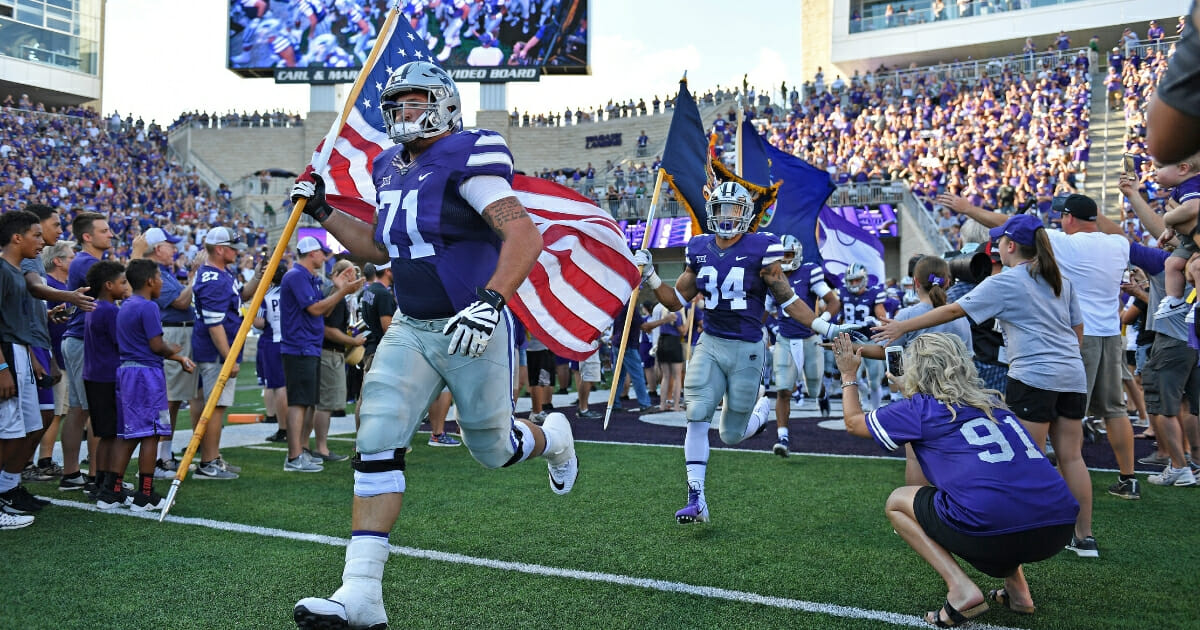 Kansas State offensive lineman Dalton Risner, left, leads the Wildcats onto the field.