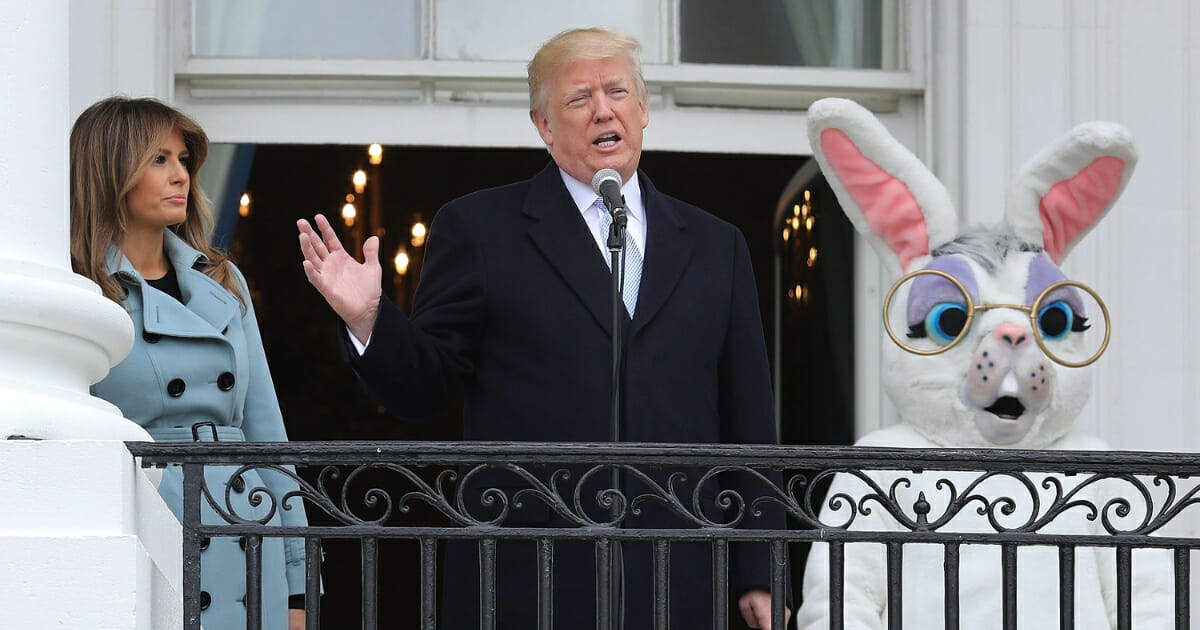 U.S. President Donald Trump (C) delivers remarks from the Truman Balcony with first lady Melania Trump during the 140th annual Easter Egg Roll on the South Lawn of the White House April 2, 2018, in Washington, D.C.