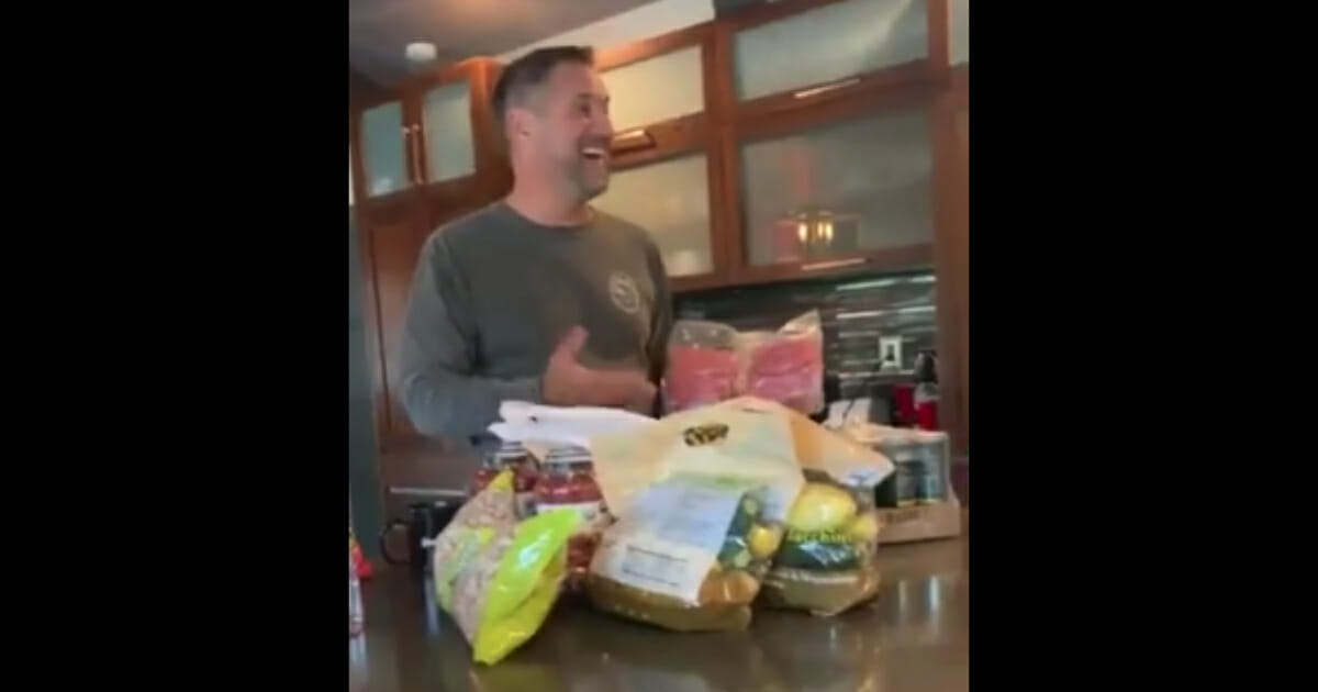 Man smiles over his giant pile of groceries.