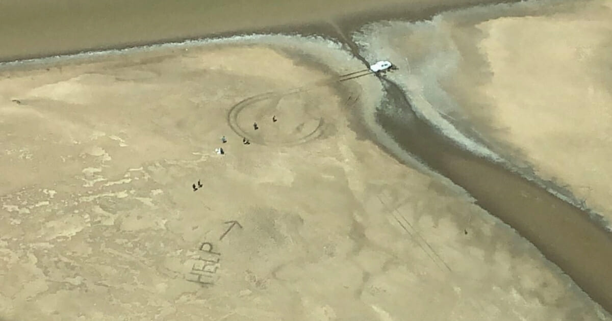 The couple was stranded but wrote "HELP" with an arrow in the mud.