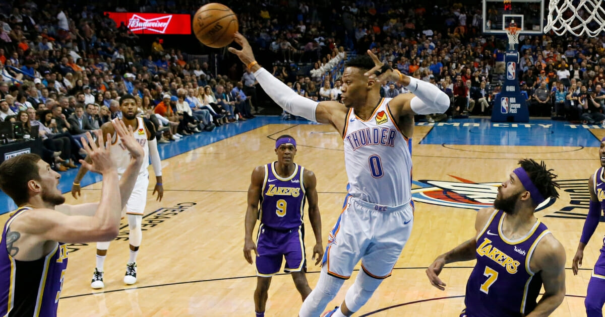 Oklahoma City Thunder guard Russell Westbrook passes to a teammate between Los Angeles Lakers forward Mike Muscala, left, guard Rajon Rondo and center JaVale McGee on April 2, 2019, in Oklahoma City.