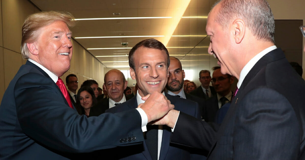 U.S. President Donald Trump shakes hands with Turkey's President Recep Tayyip Erdogan as French President Emmanuel Macron watches.