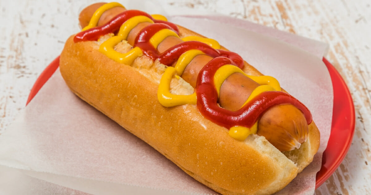 A hot dog in a bun with mustard and ketchup.