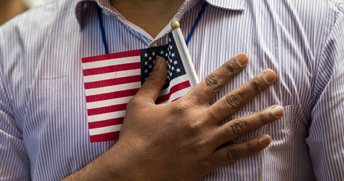 Man holding small American flag on his chest.