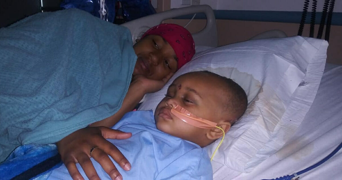 Boy in a hospital bed with his mother.