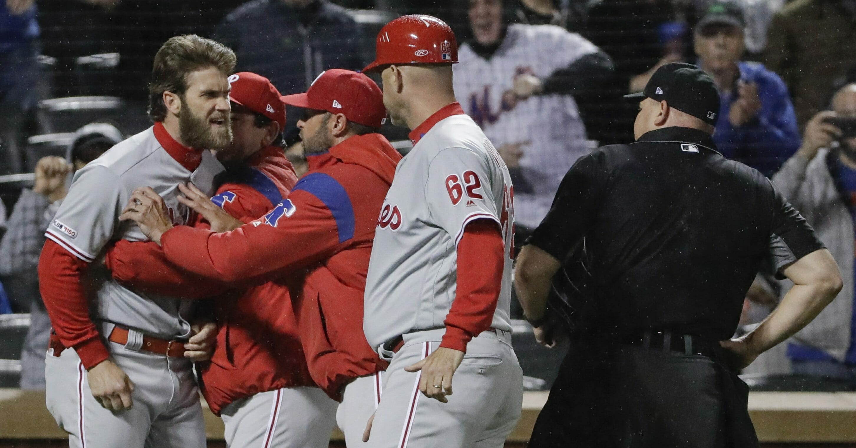 The Philadelphia Phillies' Bryce Harper, left, is restrained while arguing with umpire Mark Carlson, right.