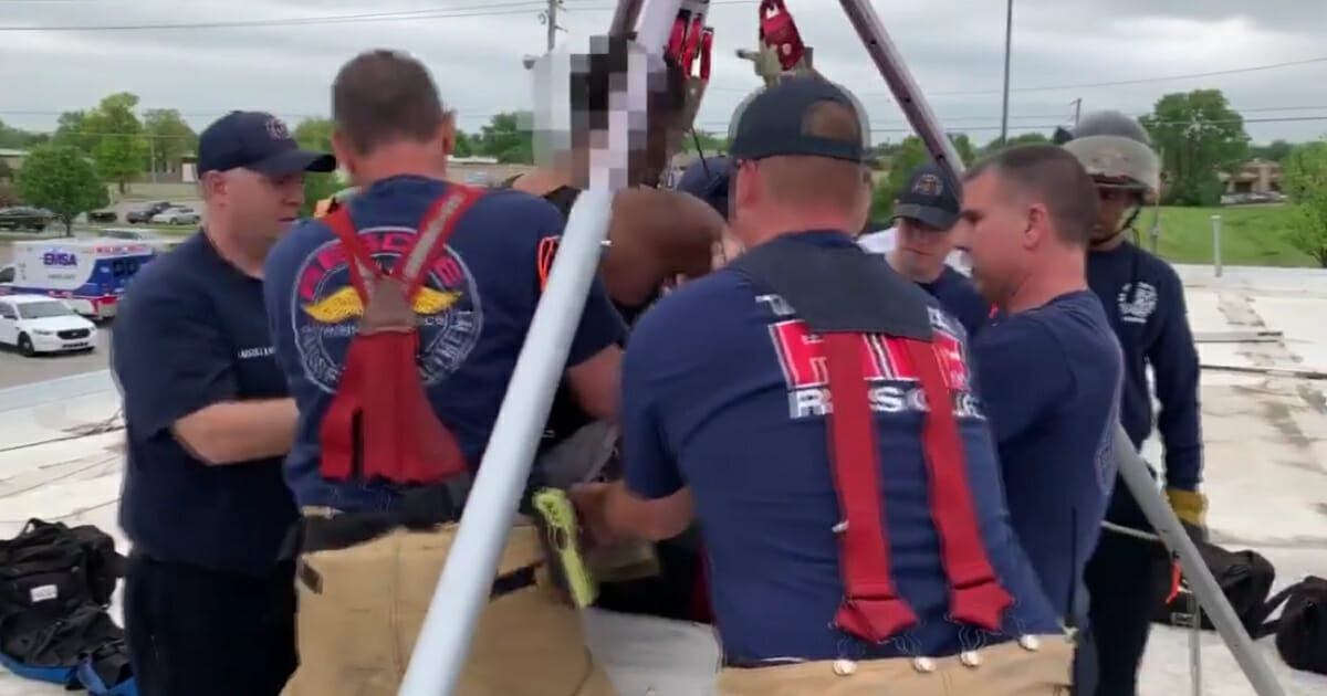 Firefighters pull man out of chimney.