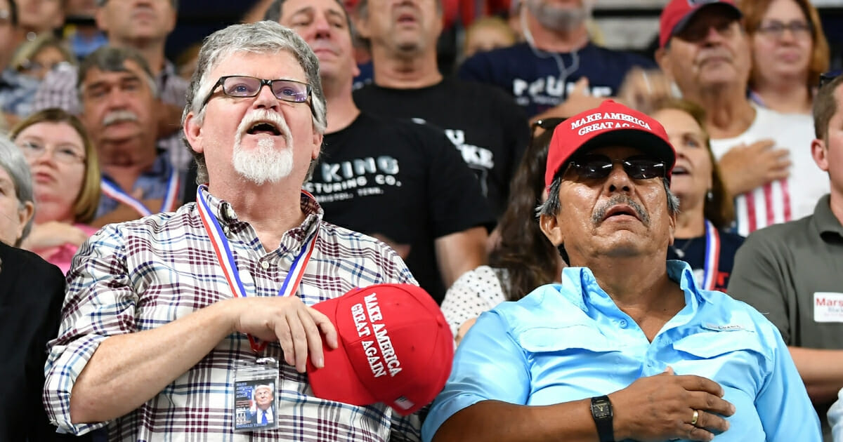 Supporters recite the Pledge of Allegiance prior to President Donald Trump speaking at a rally.