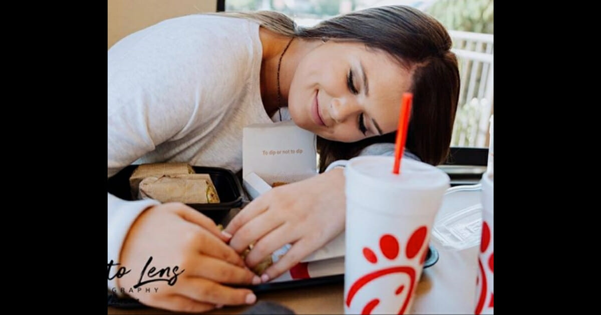 Girl smiles while hugging her Chick-fil-A meal.