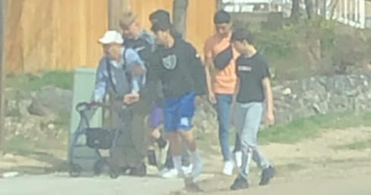 Group of boys walk an elderly man home.