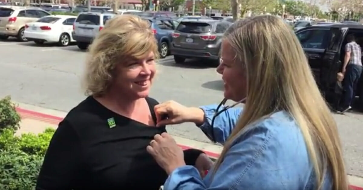 Woman listening to her son's heart beat in another woman's chest.