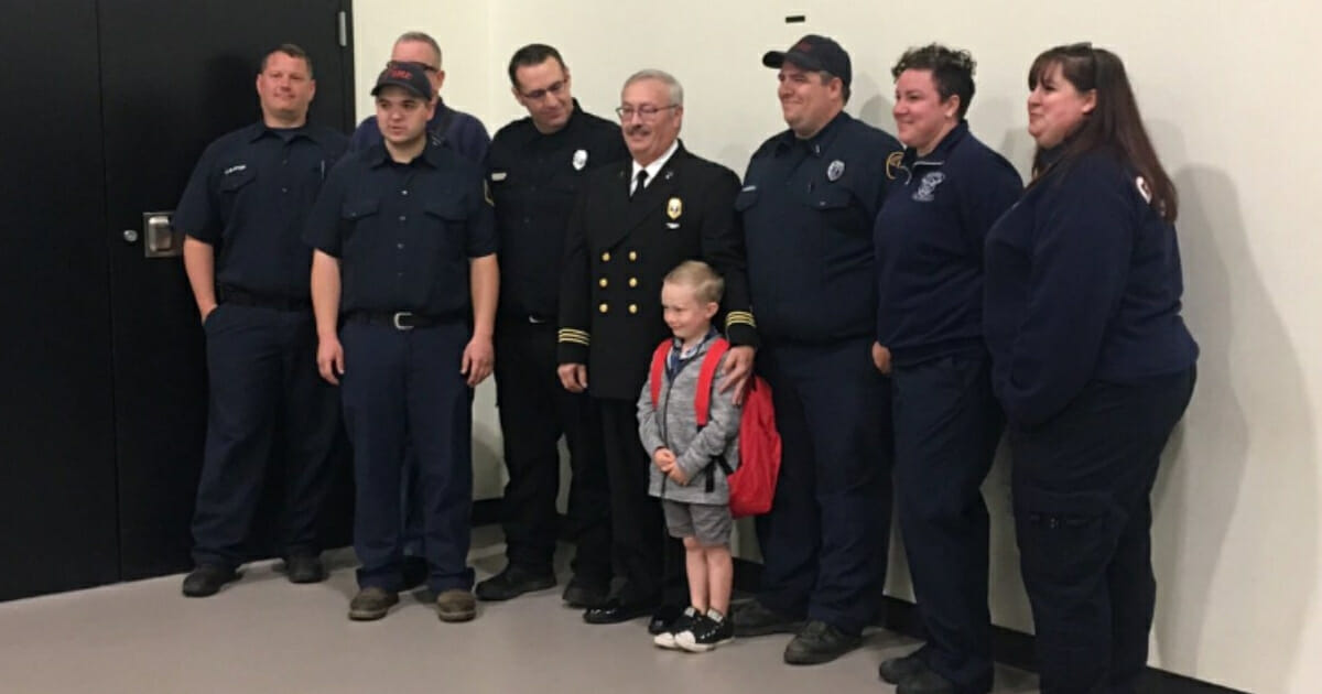 7-year-old standing with firefighters.