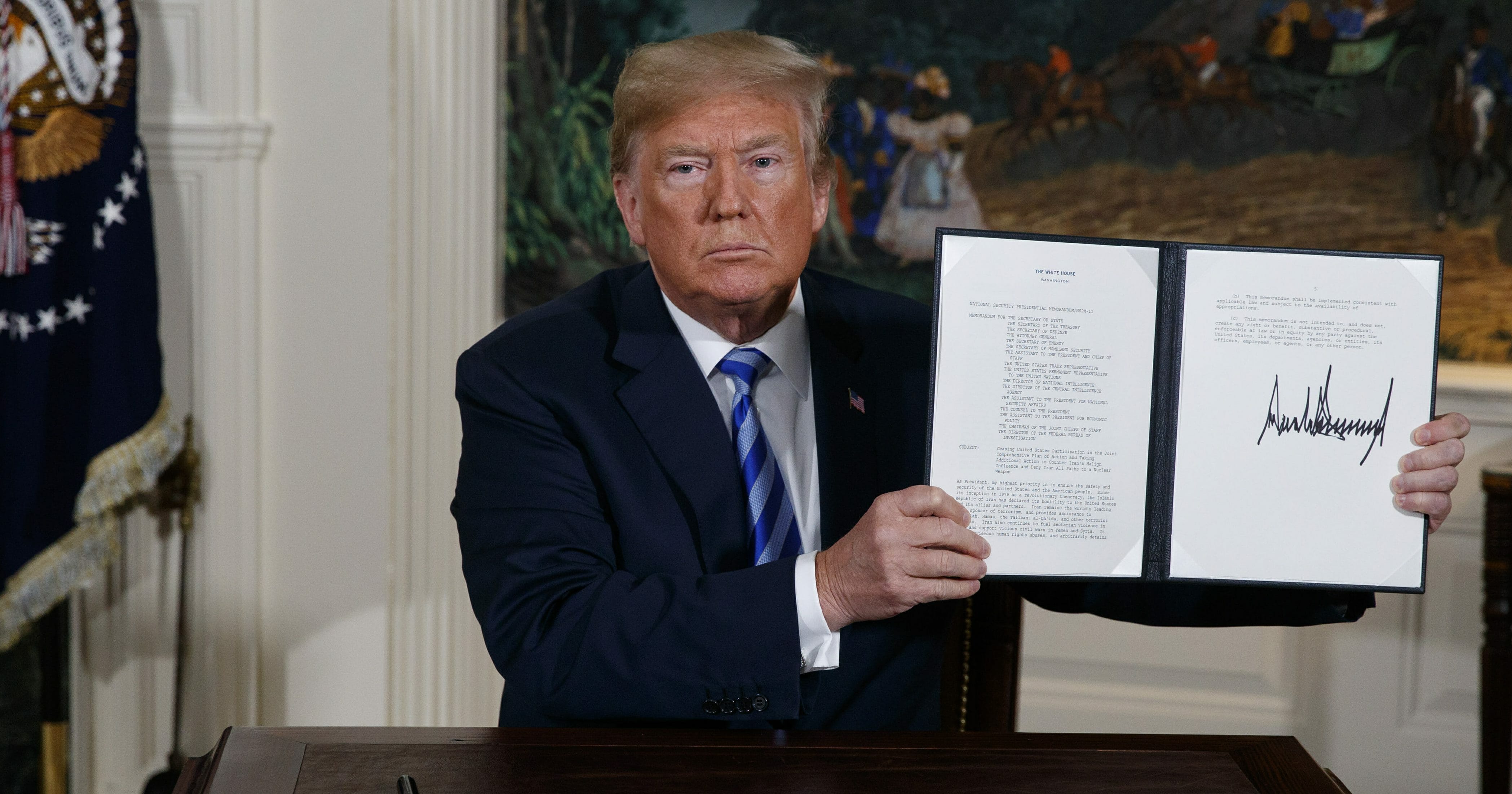 President Donald Trump shows a signed Presidential Memorandum after delivering a statement on the Iran nuclear deal in the White House on May 8, 2018.