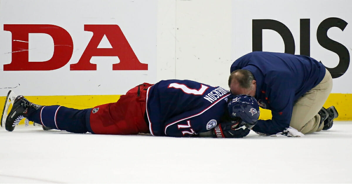 Columbus Blue Jackets athletic trainer Mike Vogt checks on Josh Anderson after he was hit in the head by Charlie McAvoy of the Boston Bruins.
