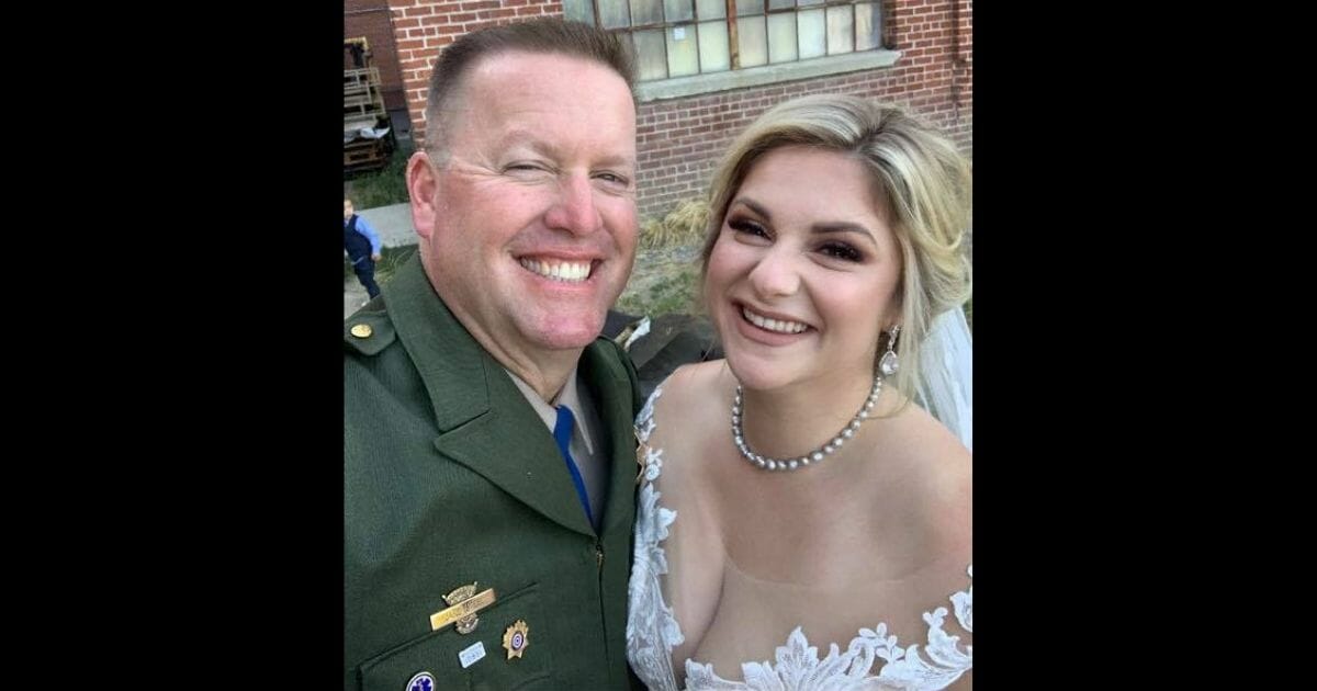 A bride stands with a police officer.