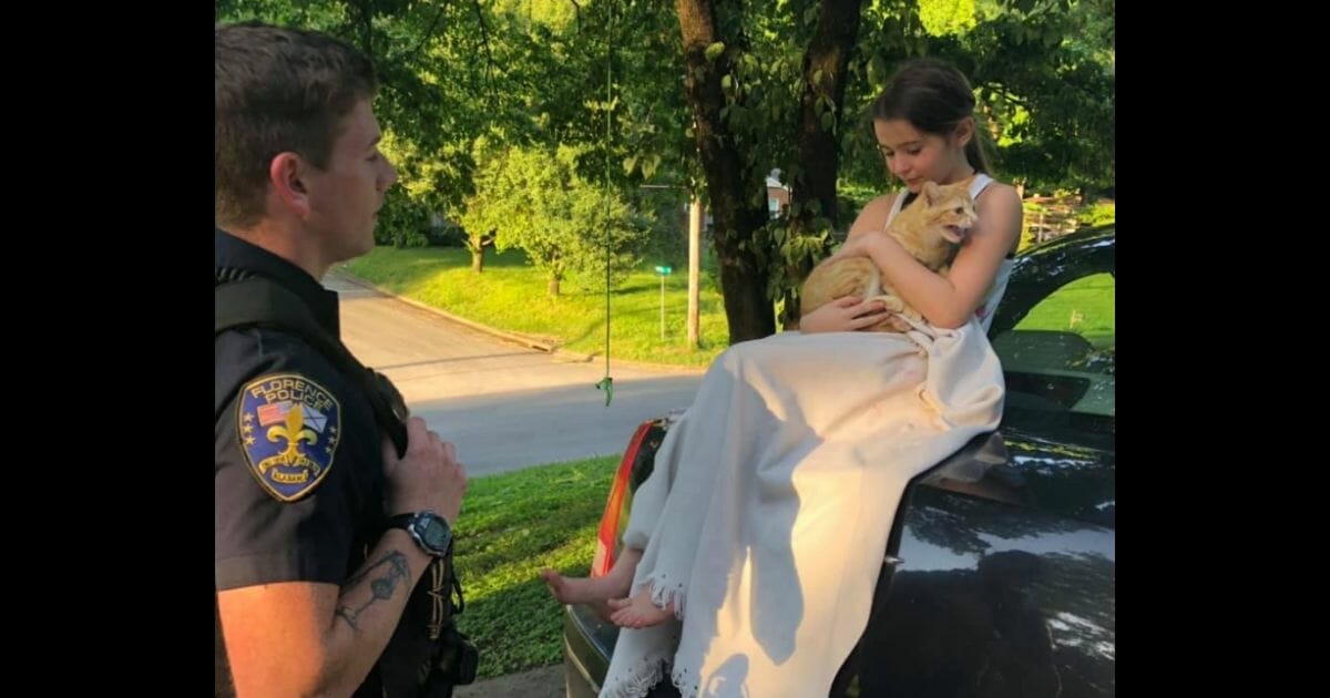Cop stands next to Makayla as she holds her new cat.