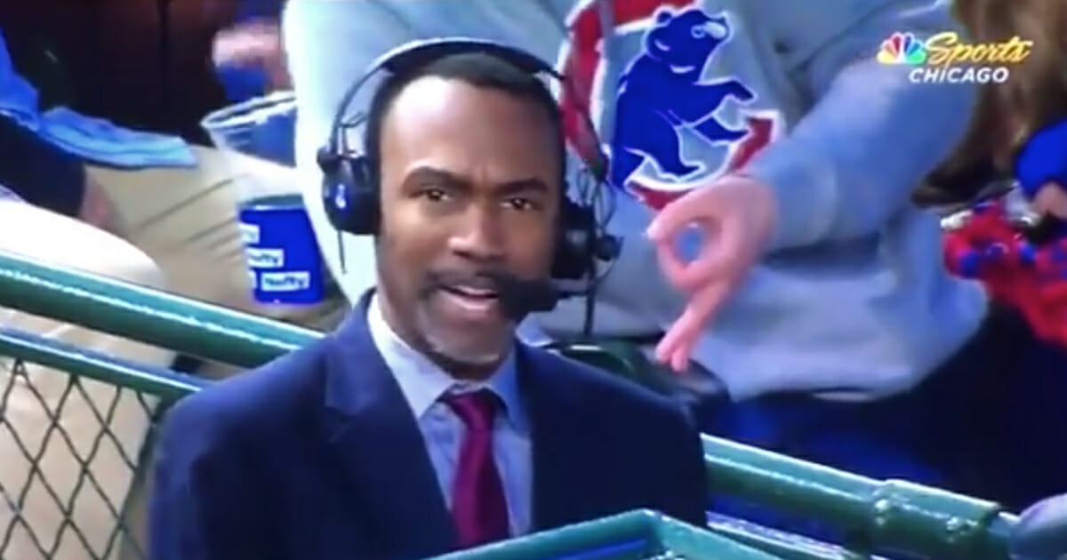 A Cubs fan makes the OK sign behind NBC Sports Chicago analyst Doug Glanville.