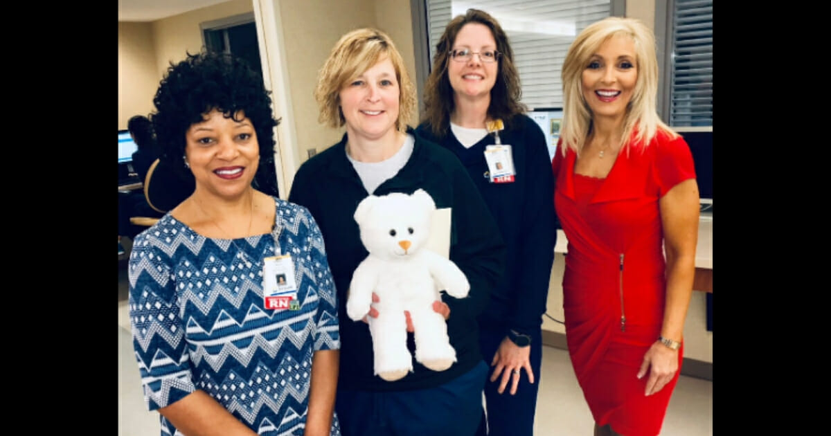 Nurses standing together, one holding a Build-A-Bear.