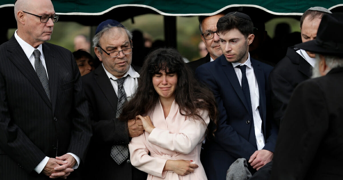 Hannah Kaye, the daughter of shooting victim Lori Kaye, center, holds the hand of her father, Howard Kaye, during funeral services, Monday, April 29, 2019, in San Diego.