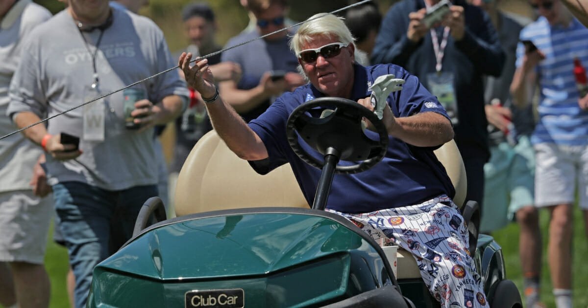 John Daly lifts a rope to get his golf cart to the 12th tee.