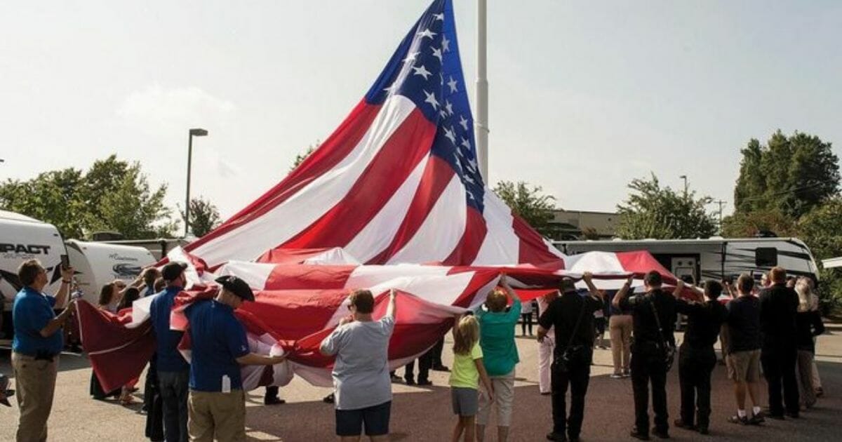 People hoisting a large flag.