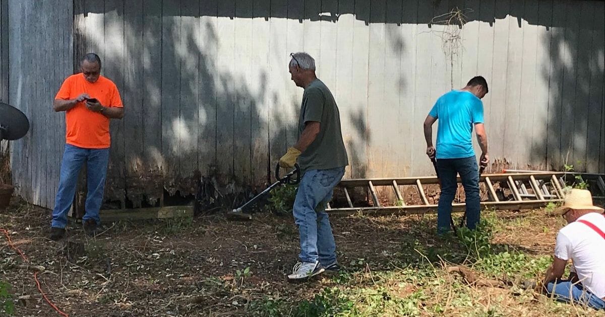 People clean up an elderly man's yard.
