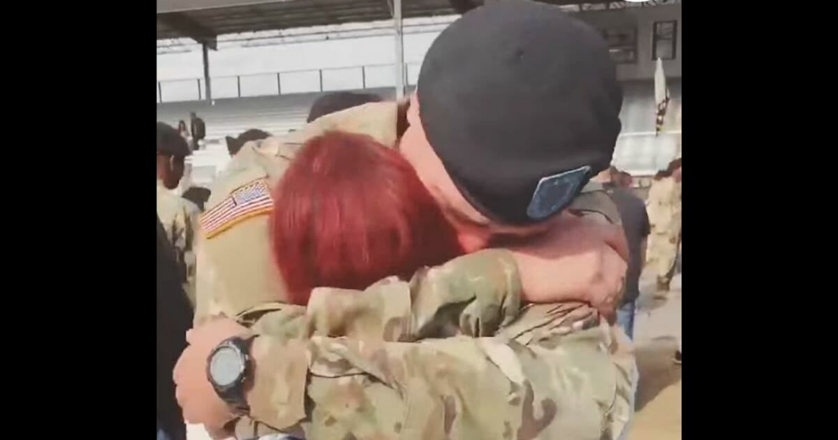 Uniformed soldier hugging woman.