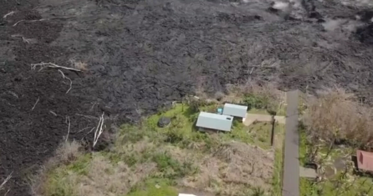 Aerial photo showing a grassy area line by charred earth and rock.