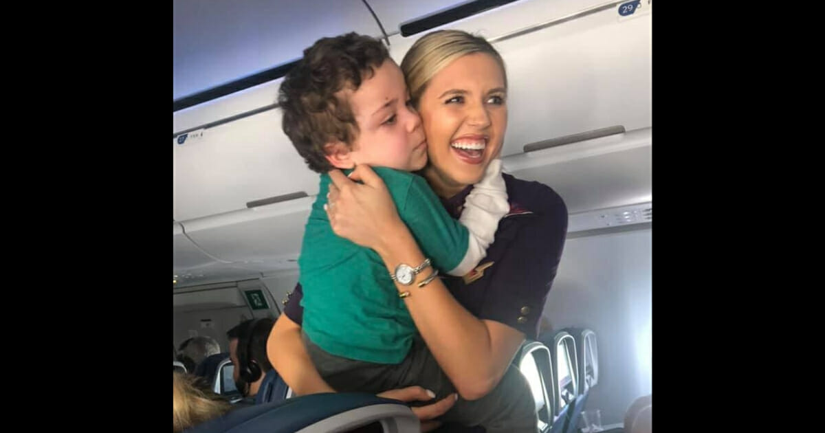 A flight attendant holds a little boy.