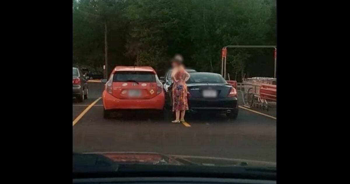 Woman looks at her car that is blocked into a spot