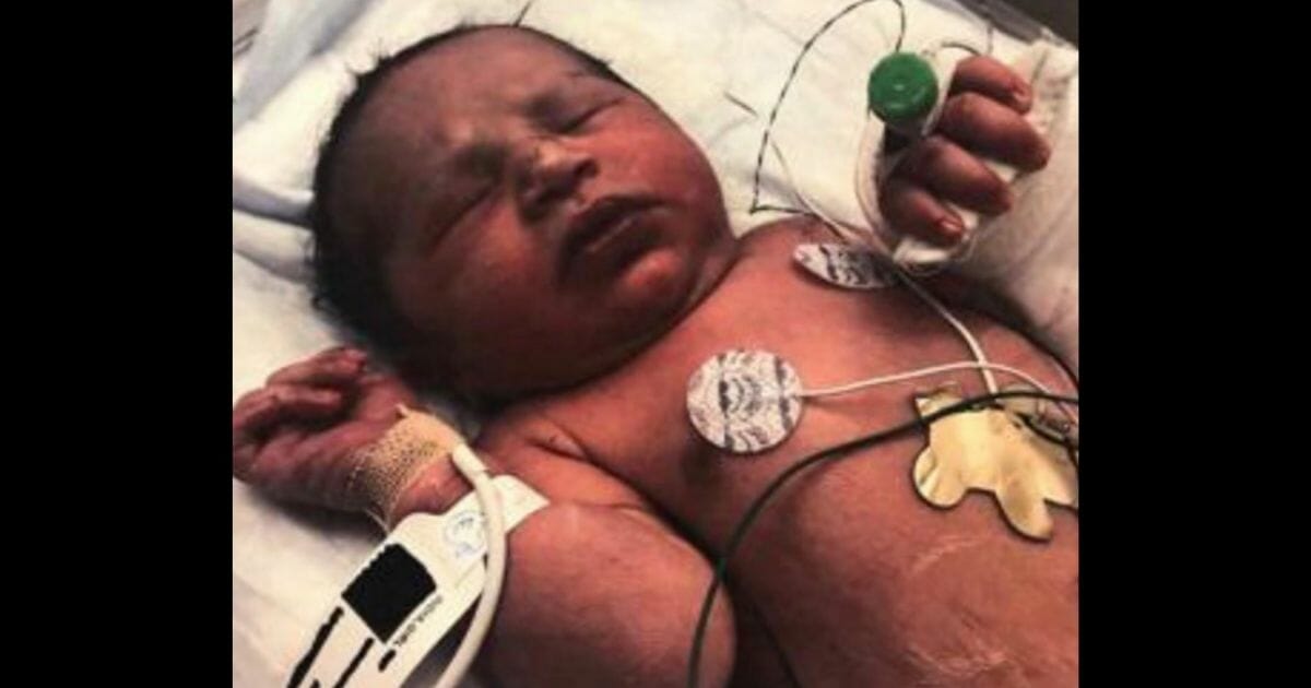 Baby lying in hospital crib.