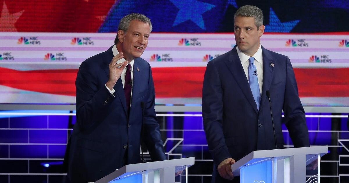 New York City Mayor Bill De Blasio, left, speaks as Ohio Rep. Tim Ryan, right, looks on during the first night of the Democratic presidential debate on June 26, 2019, in Miami, Florida.