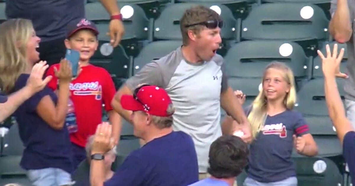 A fan in the bleachers at SunTrust Park in Atlanta celebrates after making a great catch on a grand slam by the Braves' Ronald Acuna Jr.