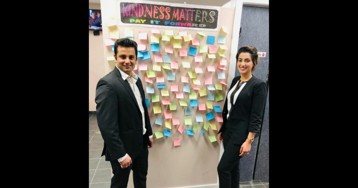 Vikas and Shivani Sanger stand next to a wall of post-it notes.