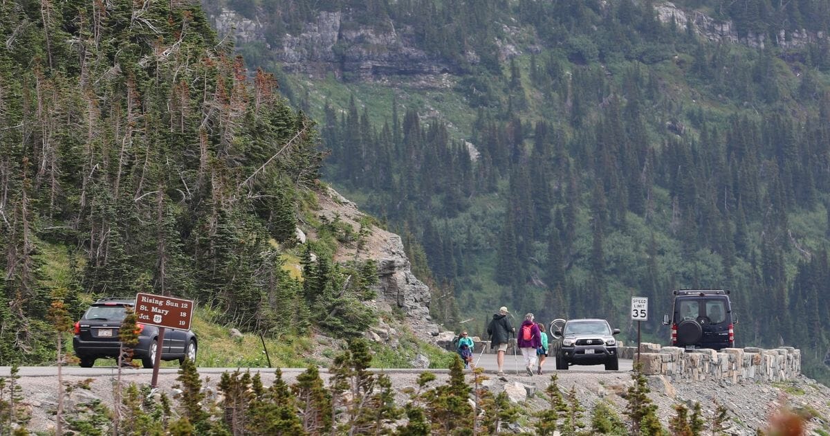 Visitors walk along the Going-to-the-Sun Road in Glacier National Park on July 26, 2018, in Montana.