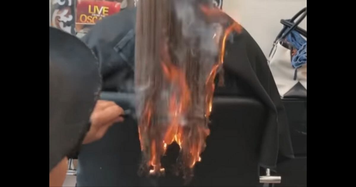 A woman's hair on fire as the stylist combs through it.