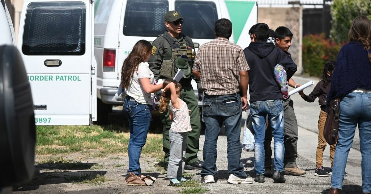 Migrant family standing with ICE officer in San Bernardino, California.