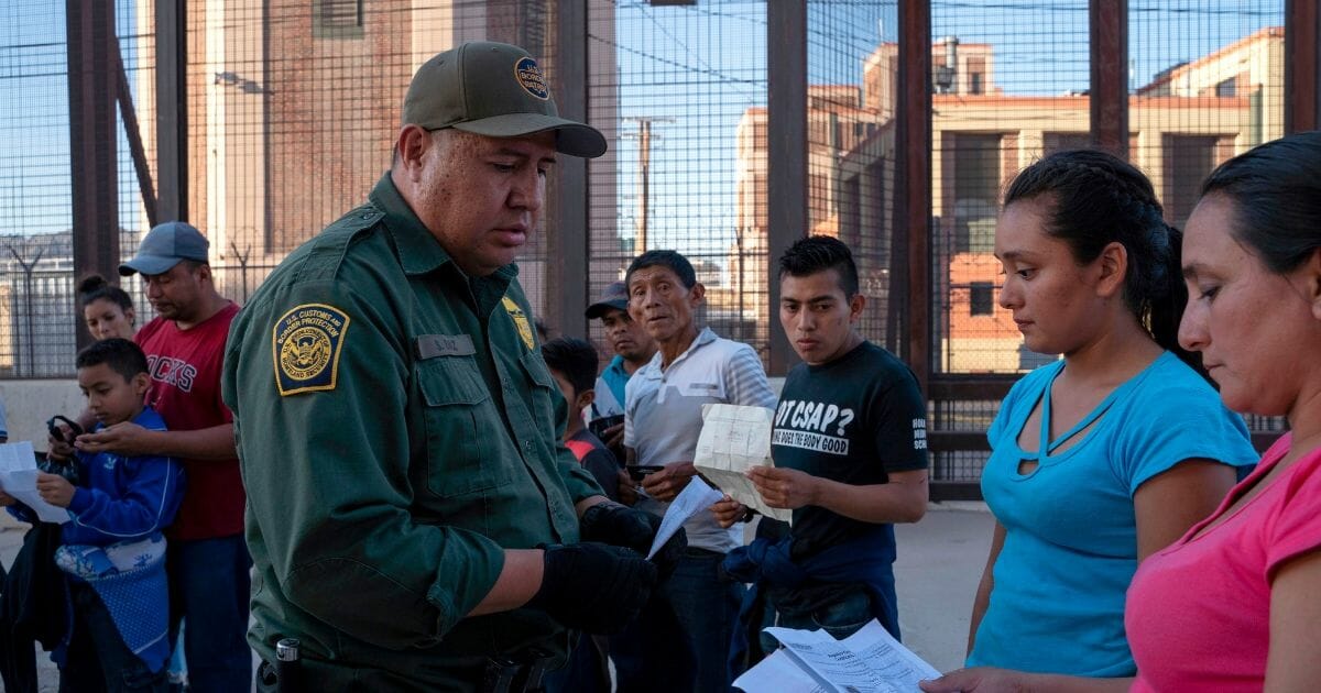 US Customs and Border Protection agent looks over migrants' documents.