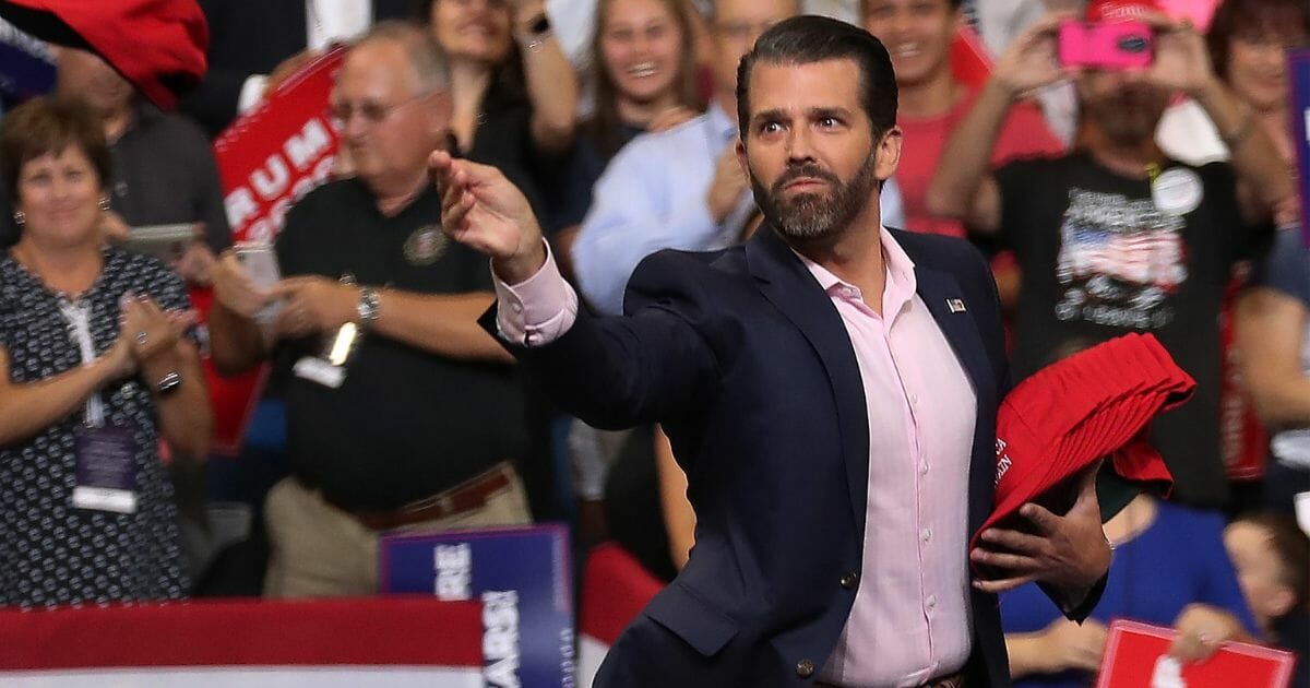 Donald Trump Jr. tosses campaign hats to the crowd before his father, President Donald Trump, arrives on stage June 18, 2019, in Orlando, Fla.
