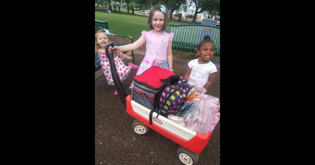Three little girls and a wagon of goody bags for the homeless in a park