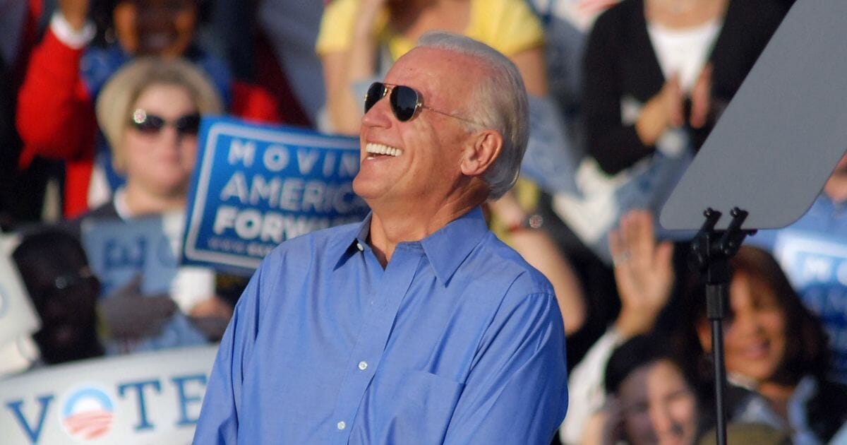 Joe Biden wearing sunglasses and laughing.