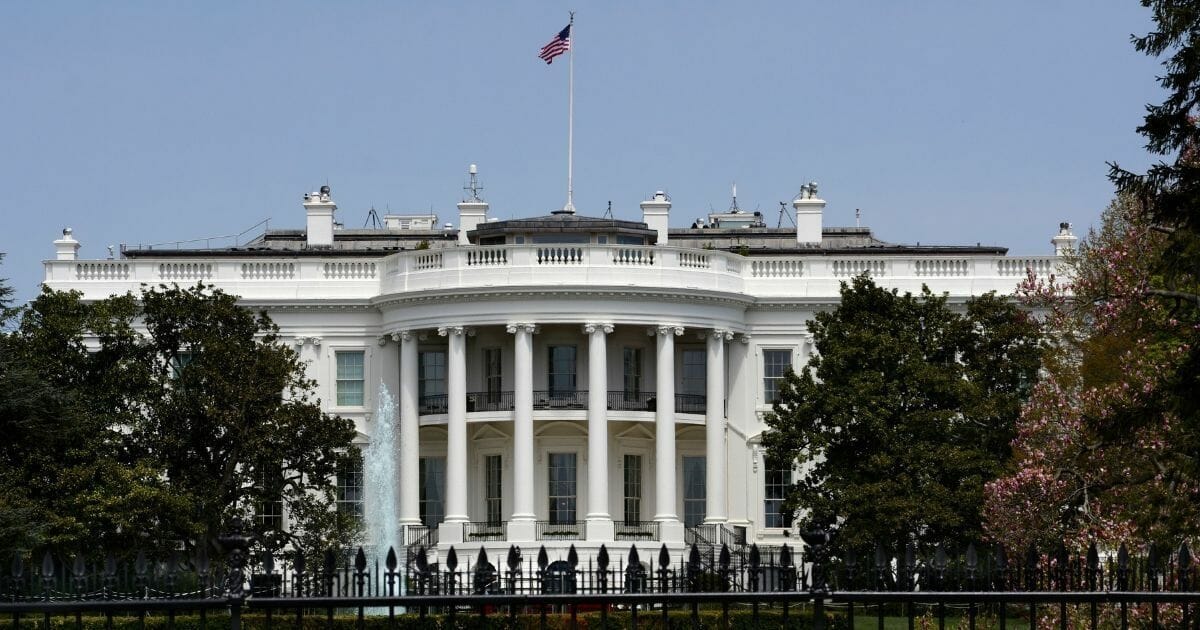 An American flag flies over the south facade of the White House in Washington, D.C. Additional security fences and barriers were added along the south perimeter to prevent people from jumping the fence and entering the restricted grounds.