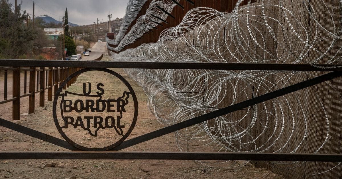 A metal fence marked with the US Border Patrol sign prevents people to get close to the barbed/concertina wire covering the US/Mexico border fence.