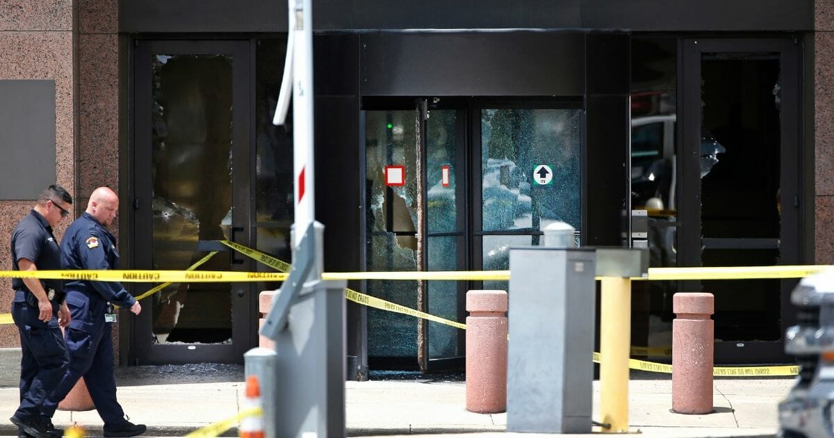 Dallas police walk past the bullet riddled glass doors of the Earle Cabell Federal Building on June 17, 2019.